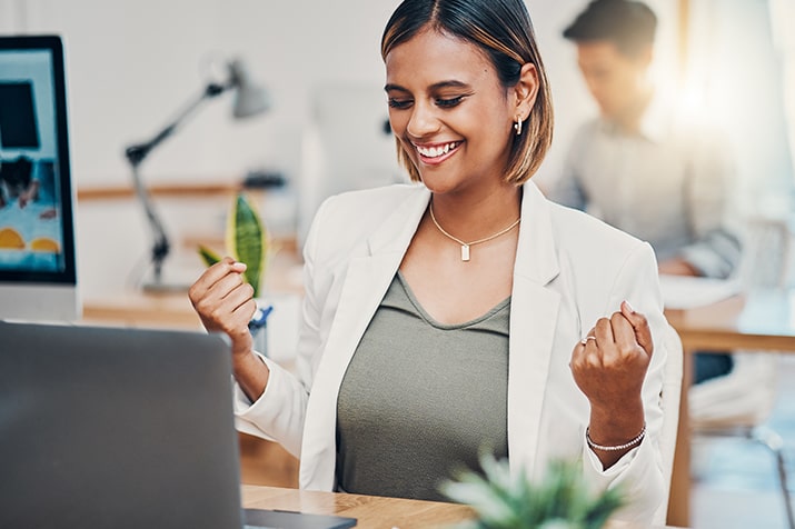 O-onboarding-de-clientes-SULTS - Blog SULTS Onboarding de clientes - empresária feliz e comemorando sucesso em frente ao notebook no escritório.