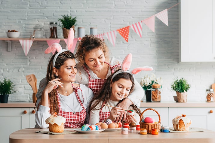 Comercio-varejista-SULTS - Blog SULTS Comércio varejista - mãe, filha e avó com roupas personalizadas para a Páscoa fazendo decoração para a data comemorativa.
