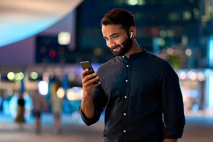 Mobile-learning-SULTS - Blog SULTS Mobile learning - homem com fones de ouvido olhando para smartphone em mãos, sorrindo.