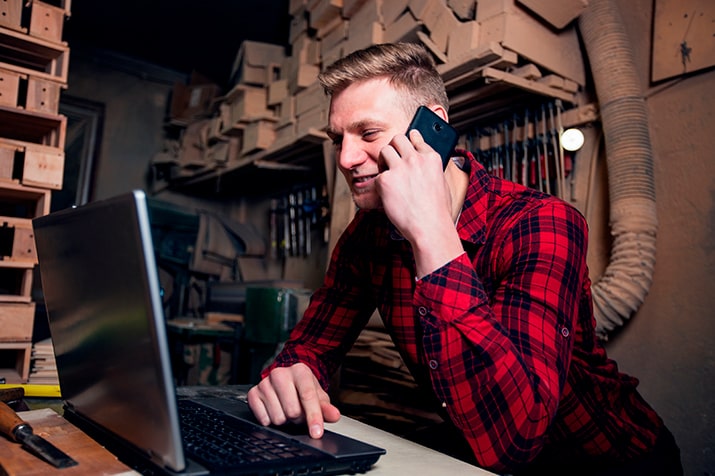 Rede-material-de-construcao-SULTS - Blog SULTS Material de construção - empresário sorrindo falando ao telefone e usando laptop.