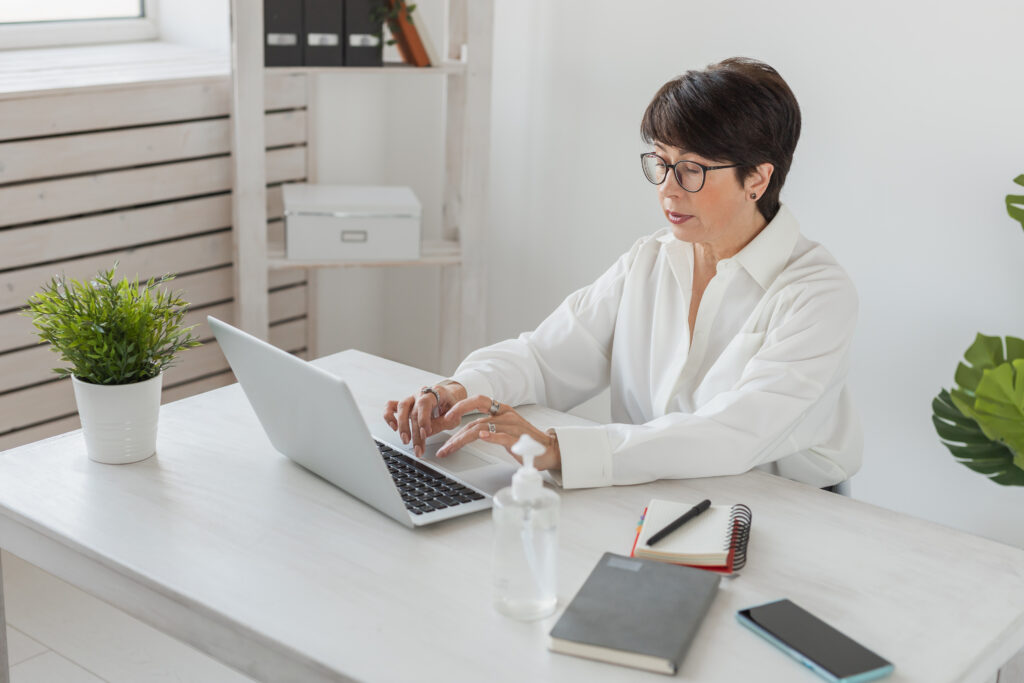 Attractive mature business woman working on laptop in her workstation - manager and office concept - Blog SULTS