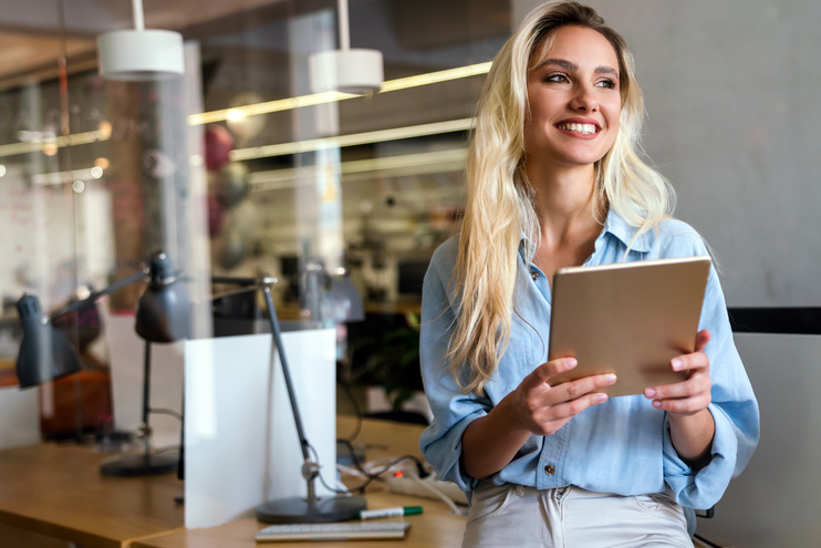 Portrait of an attractive young businesswoman smiling working on digital tablet in office - Blog SULTS
